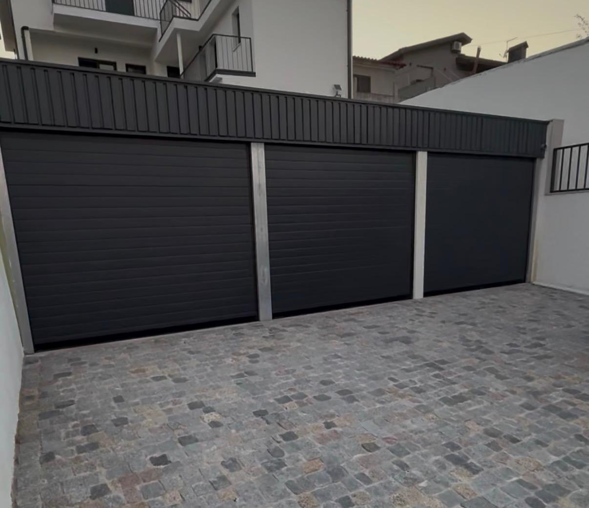 Três portas seccionais de garagem pretas lado a lado